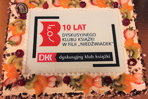 tort z napisem 10 lat i logiem biblioteki oraz dyskusyjnego klubu książki