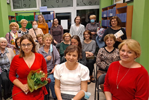 grupa osób siedzi na krzesłach w bibliotece