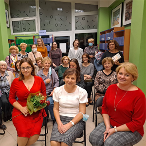 grupa osób siedzi na krzesłach w bibliotece