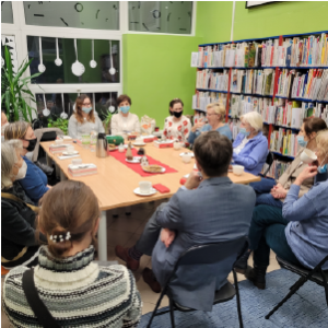 Grupa dwunastu osób dyskutuje przy stole