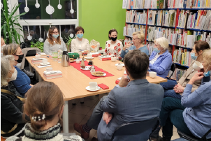 Grupa dwunastu osób dyskutuje przy stole