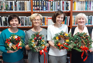 Cztery panie pozują ze stroikami świątecznymi w ręku.