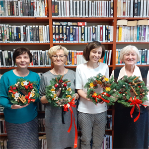 Cztery panie pozują ze stroikami świątecznymi w ręku.