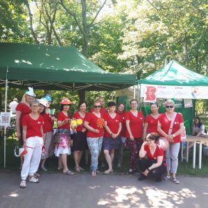 Piknik Czerwiec ’76 czternaście osób w czerwonych koszulkach stoi przed zielonymi namiotami