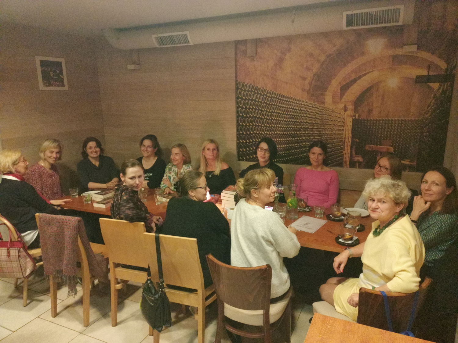 Dyskusyjny Klub Książki kilkanaście kobiet siedzi w kawiarni przy stole