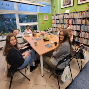 kobiety siedzą wokół stołu, na którym leżą książki