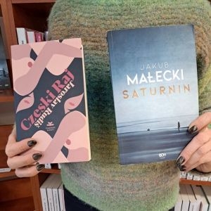 osoba trzyma dwie książki i pokazuje ich okładki