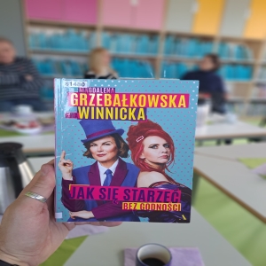 Książka trzymana w dłoni. Na okładce zdjęcia dwóch kobiet. Książka „Jak się starzeć bez godności” Magdaleny Grzebałkowskiej i Ewy Winnickiej.