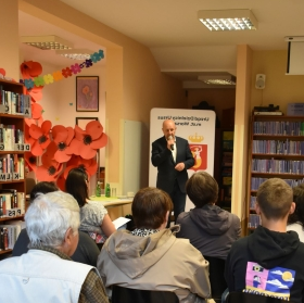 ludzie siedzą i słuchają człowieka z mikrofonem