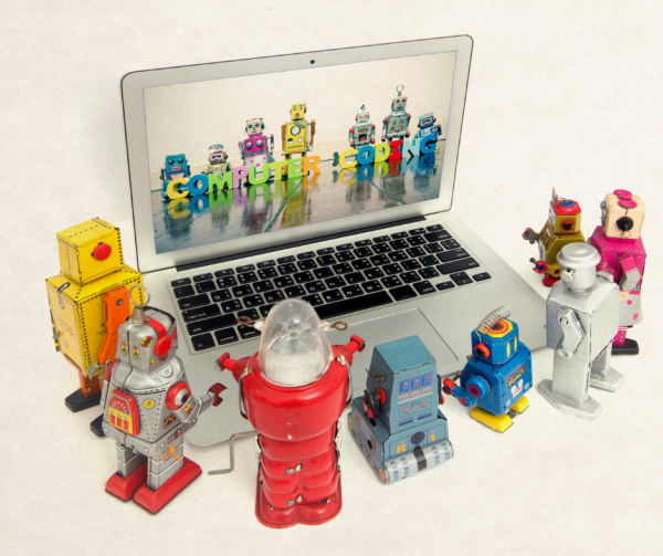 grupa robotów przed laptopem, na ekranie laptopa również grupa robotów