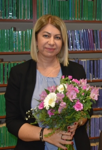 kobieta z bukietem kwiatów stoi na tle półek z książkami