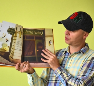 mężczyzna w czapce z daszkiem pokazuje wnętrze książki