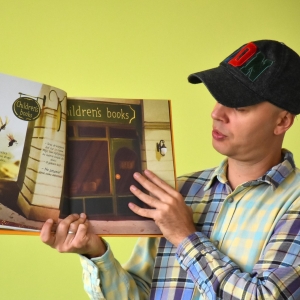 mężczyzna w czapce z daszkiem pokazuje wnętrze książki