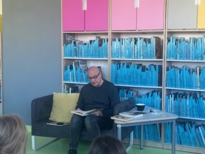 mężczyzna siedzi na tle półek z książkami