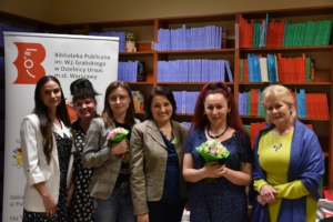 sześć kobiet pozuje do zdjęcia na tle półek z książkami