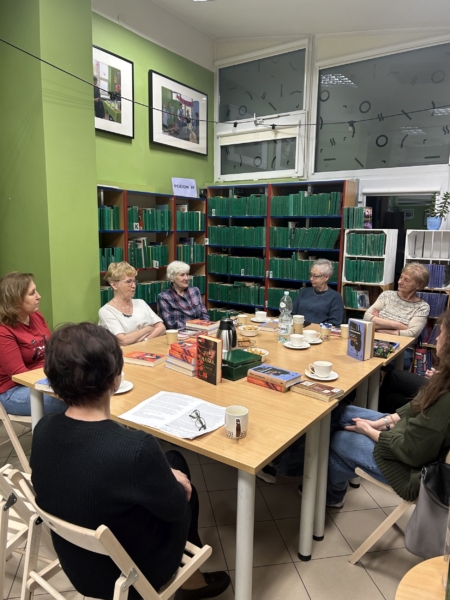 Dyskusyjny Klub Książki grupa kobiet siedzi wokół stołu w bibliotece i rozmawia ze sobą