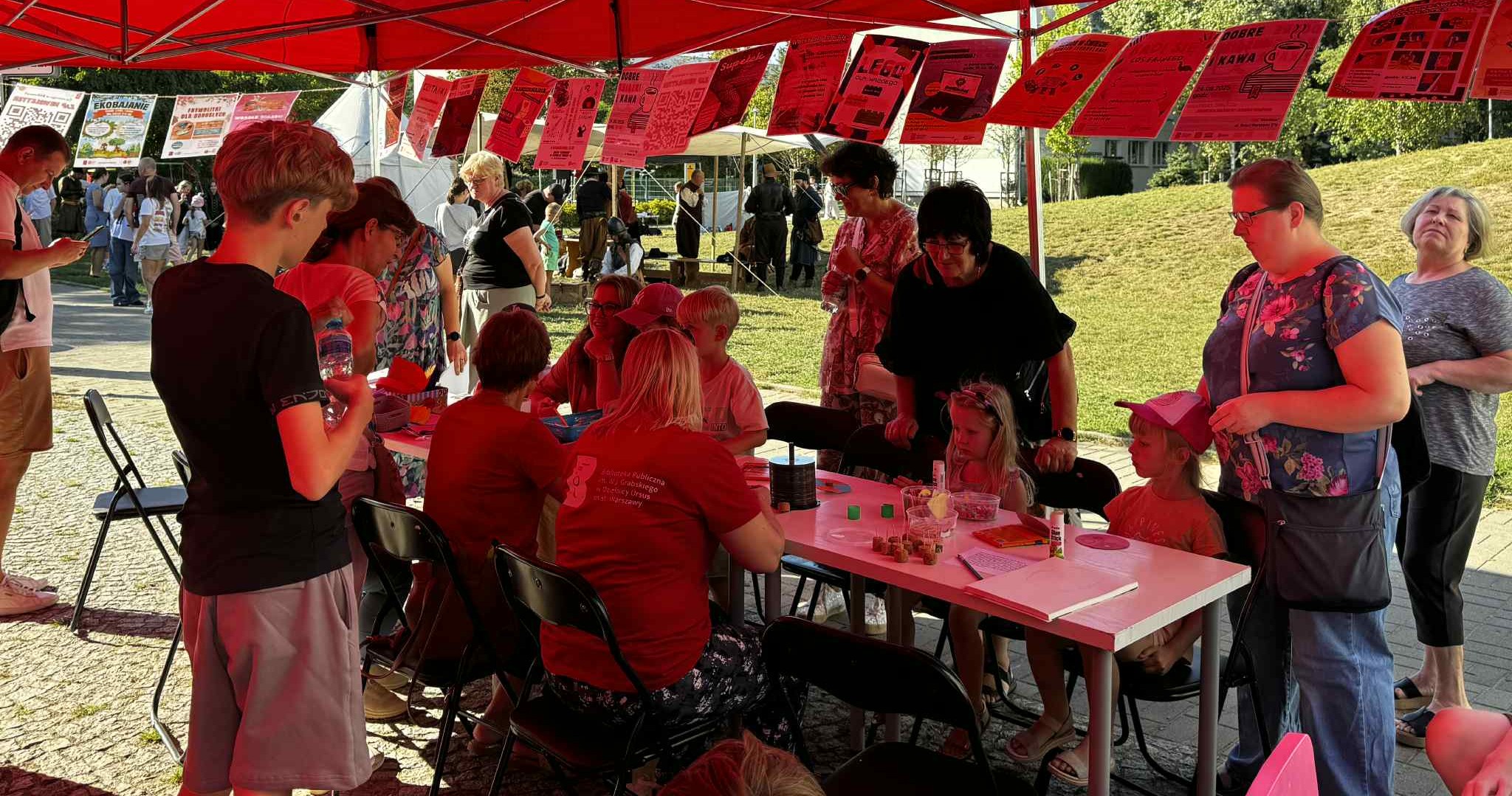 4e56321a-f893-4c3a-8bf3-fcb04554544c Dzieci tworzą prace plastyczne pod czerwonym namiotem