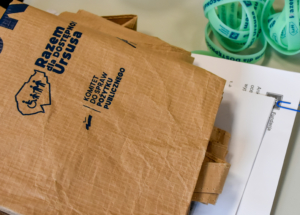 Brązowa torba, obok leży kilka zielonych opasek