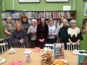 Grupa kobiet stoi wokół stołu z książkami, rozmawiając i przeglądając materiały