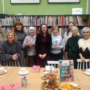 Grupa kobiet stoi wokół stołu z książkami, rozmawiając i przeglądając materiały