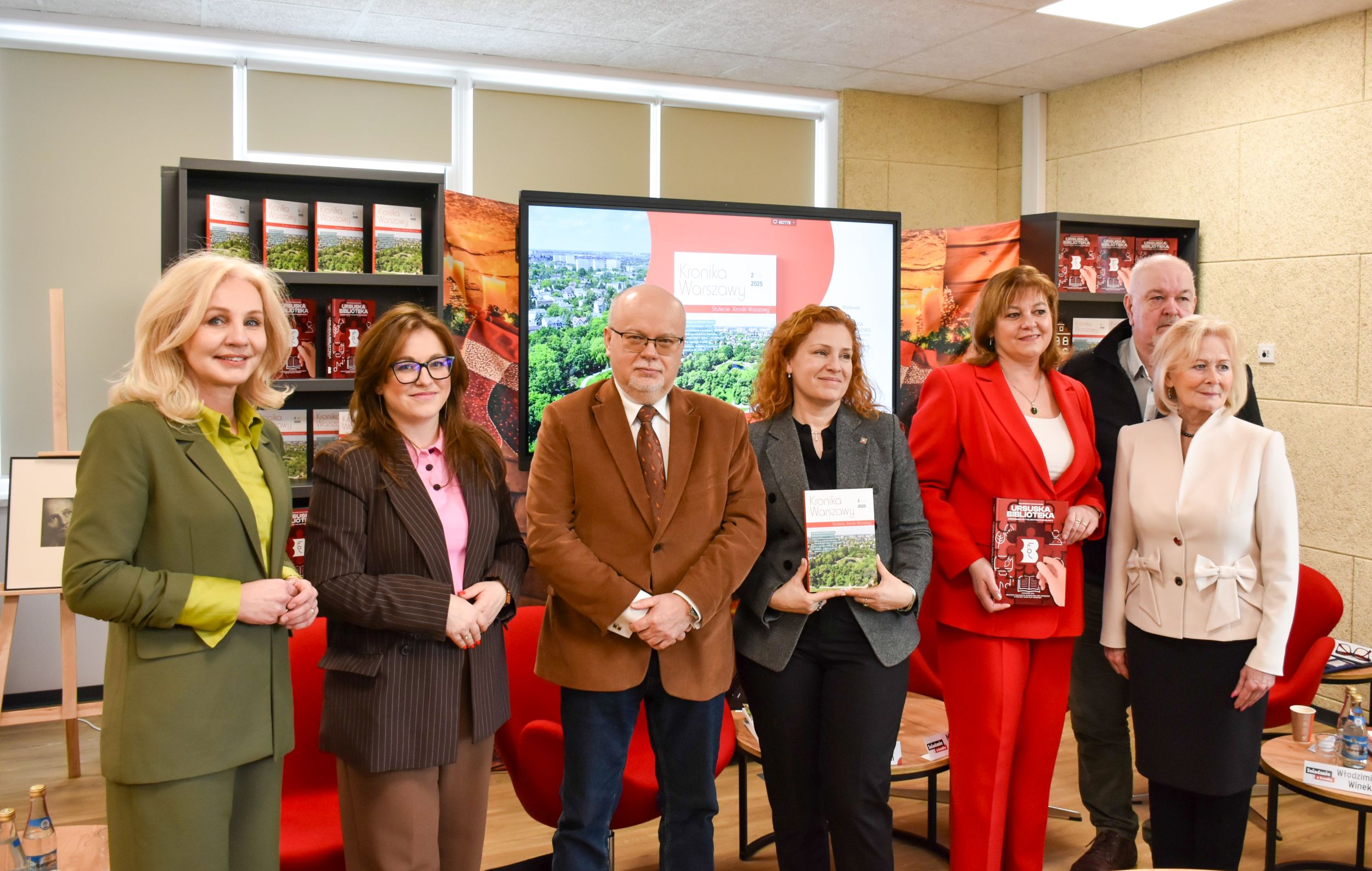 1 Grupa ludzi stoi przed ekranem, angażując się w prezentację lub dyskusję.