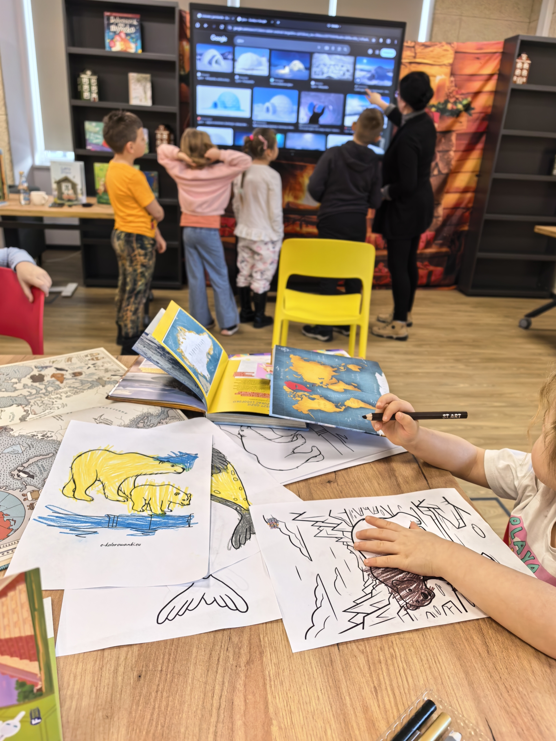 _cuva Dzieci siedzą przy stole z książkami, obok telewizor, w przytulnym pomieszczeniu