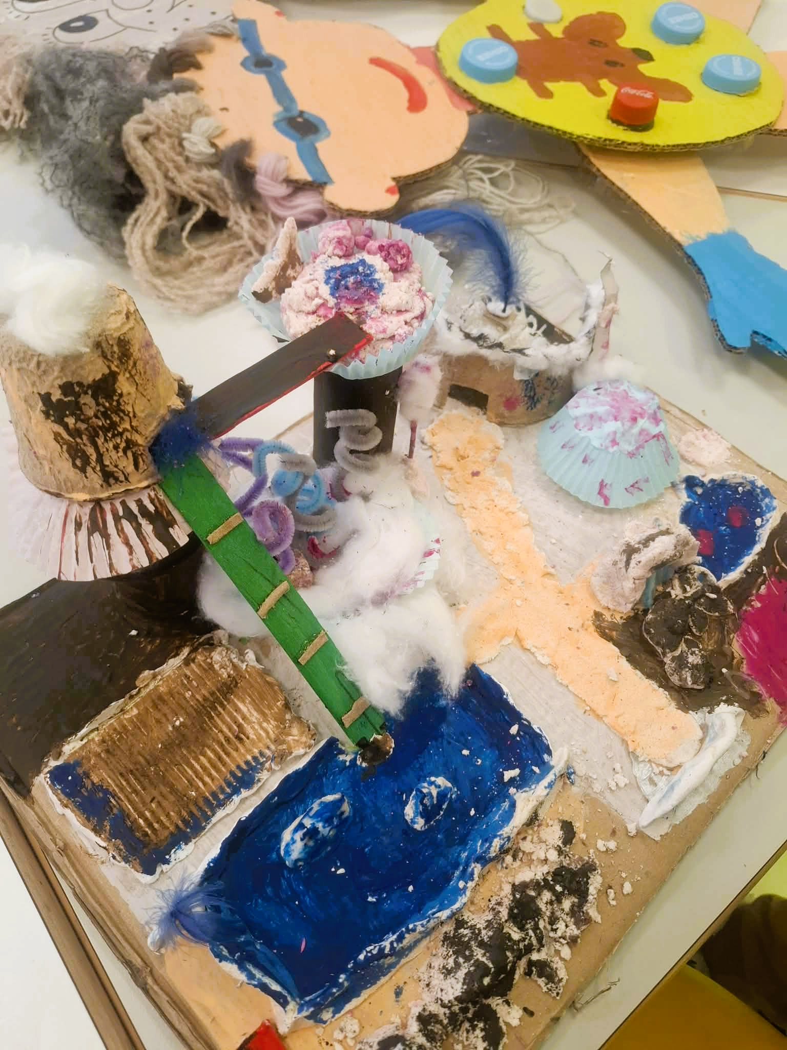 Biblioteka. (2) Stół z różnorodnymi papierowymi rzemiosłami, w tym origami i wycinankami, rozłożonymi na jego powierzchni