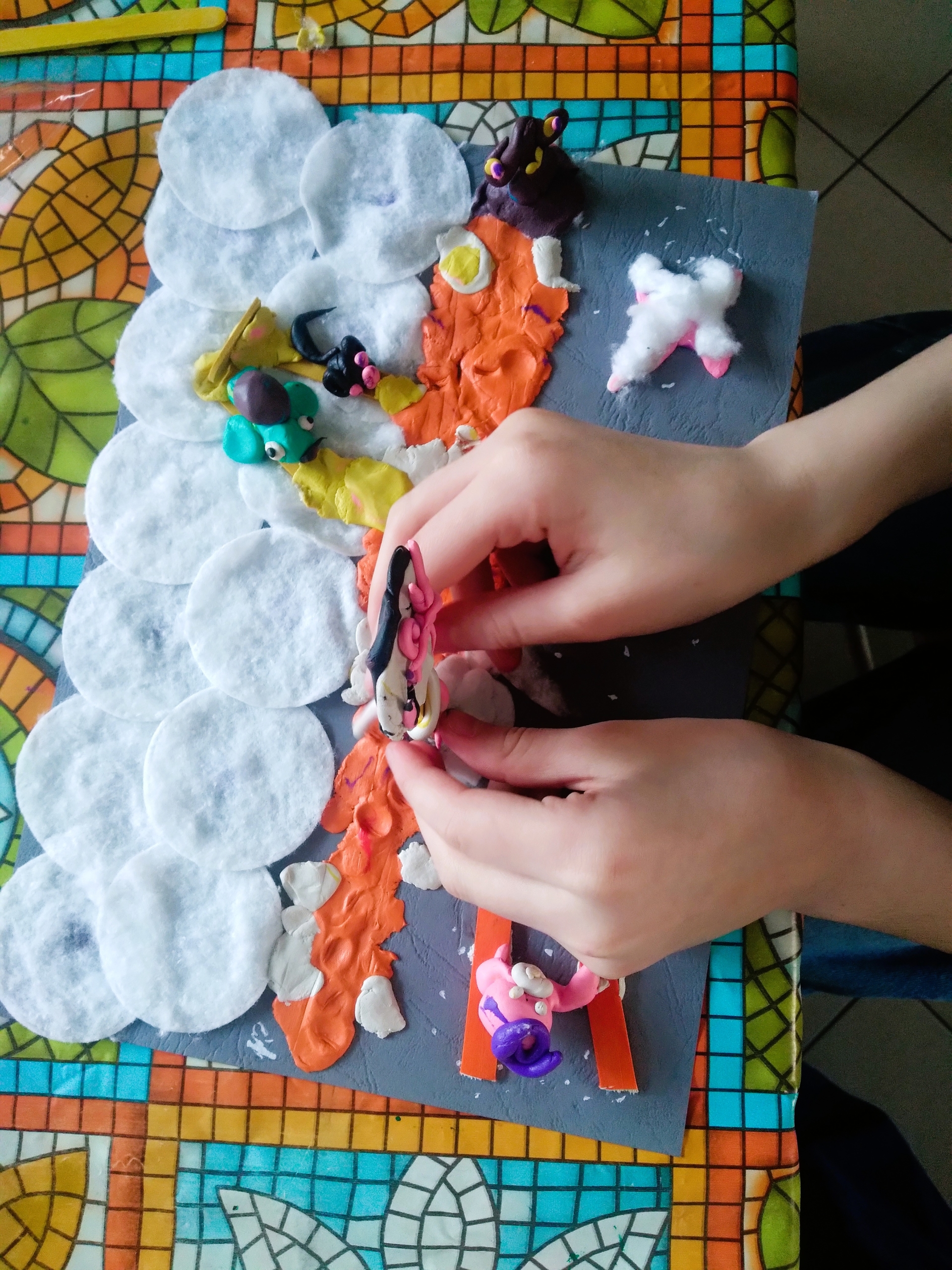 Biblioteka. (3) Dziecko tworzy pracę plastyczną z plasteliny i płatków bawełnianych, obok leży zabawkowy samochód