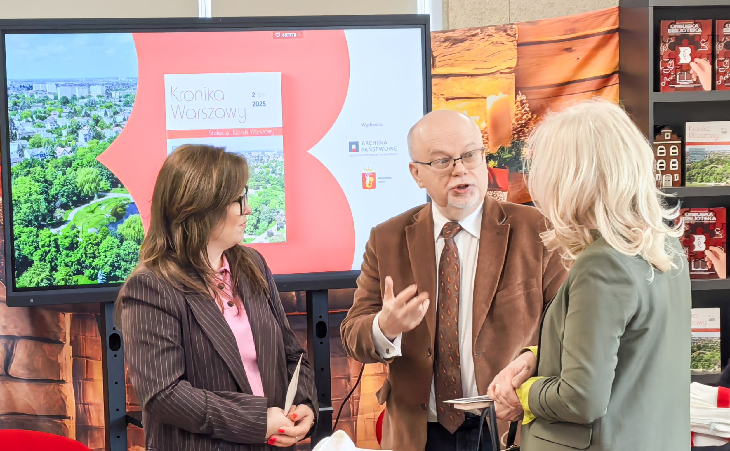 _cuva Mężczyzna w okularach brązowym garniturze krawacie i białej koszuli z pasją opowiada dwóm kobietom historię