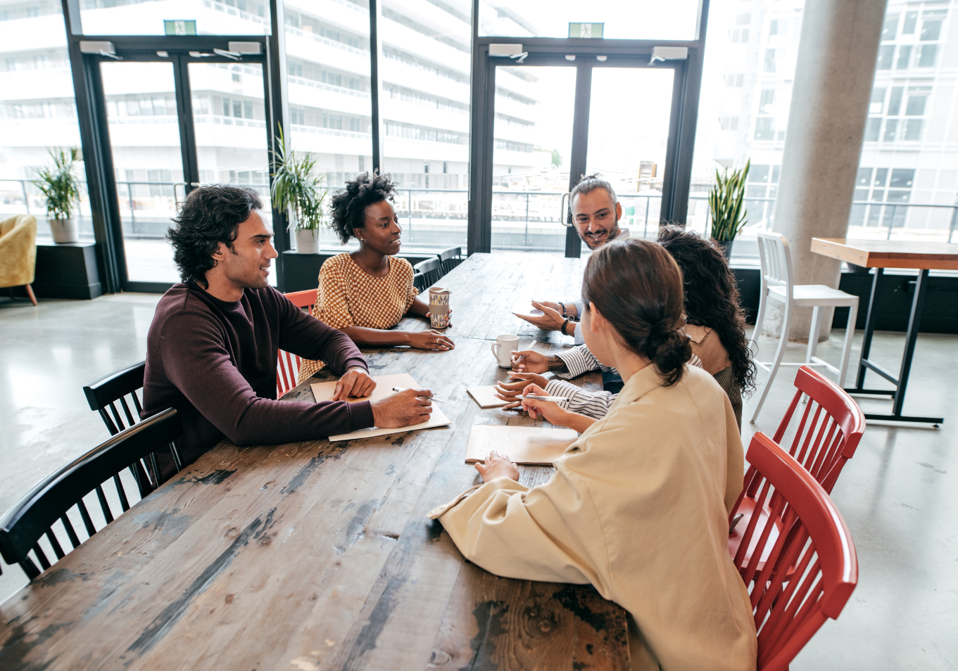 Grupa ludzi siedzi przy stole w biurze, prowadząc dyskusję w profesjonalnej atmosferze.