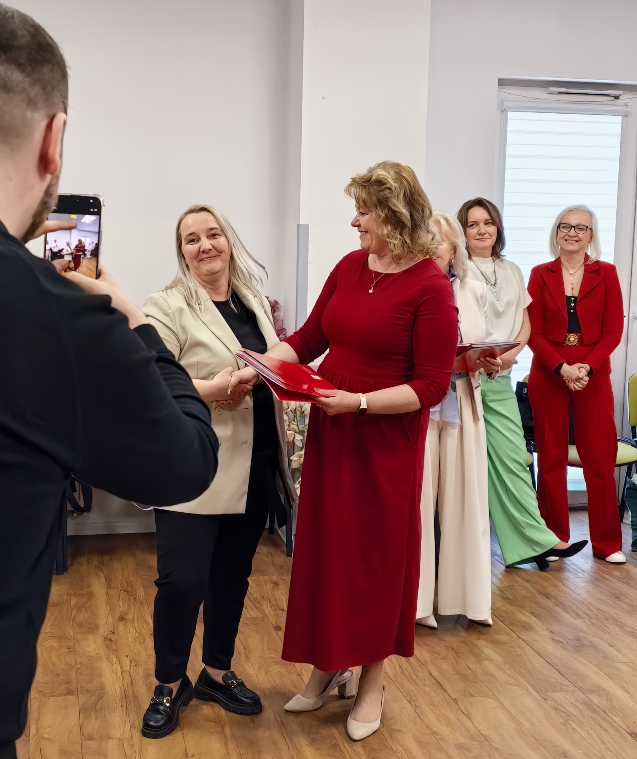 _cuva Kilka kobiet pozujących mężczyźnie do zdjęcia. Mężczyzna trzyma w dłoniach telefon.