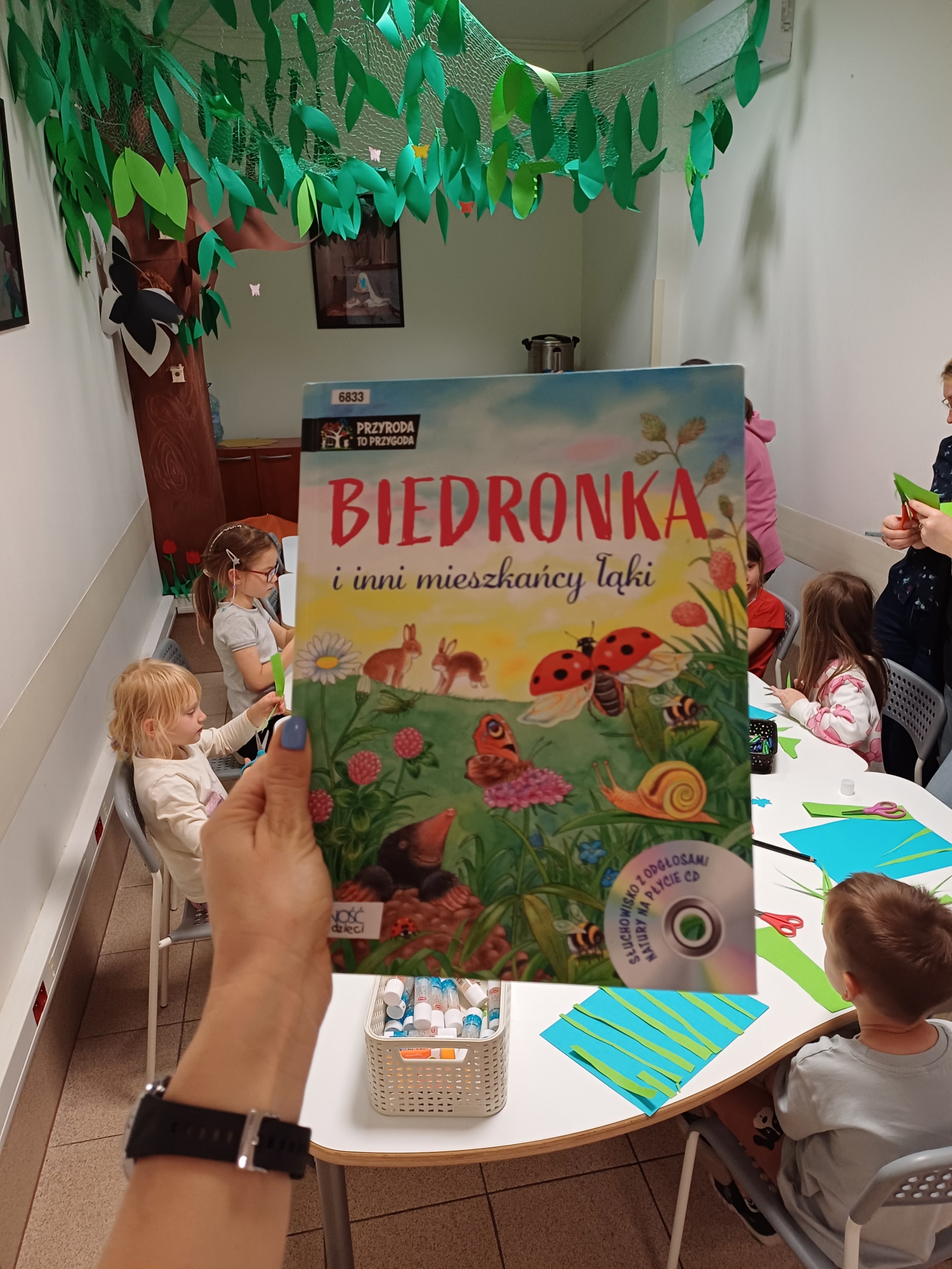 20250611_163532 Ręka, która trzyma książkę dziecięcą.