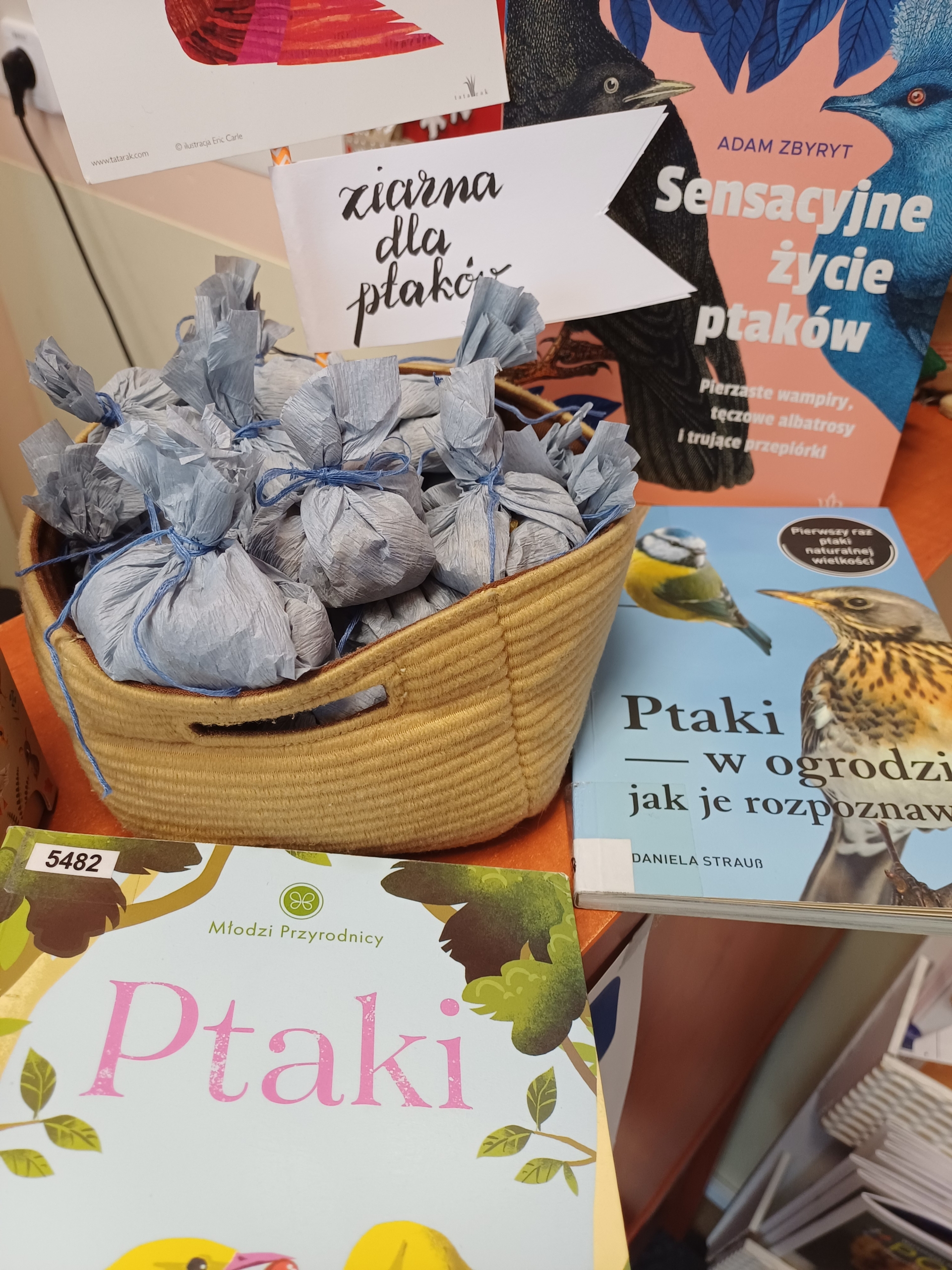 20260113_110544 Koszyk z zawiniątakmi oraz książki o ptakach.