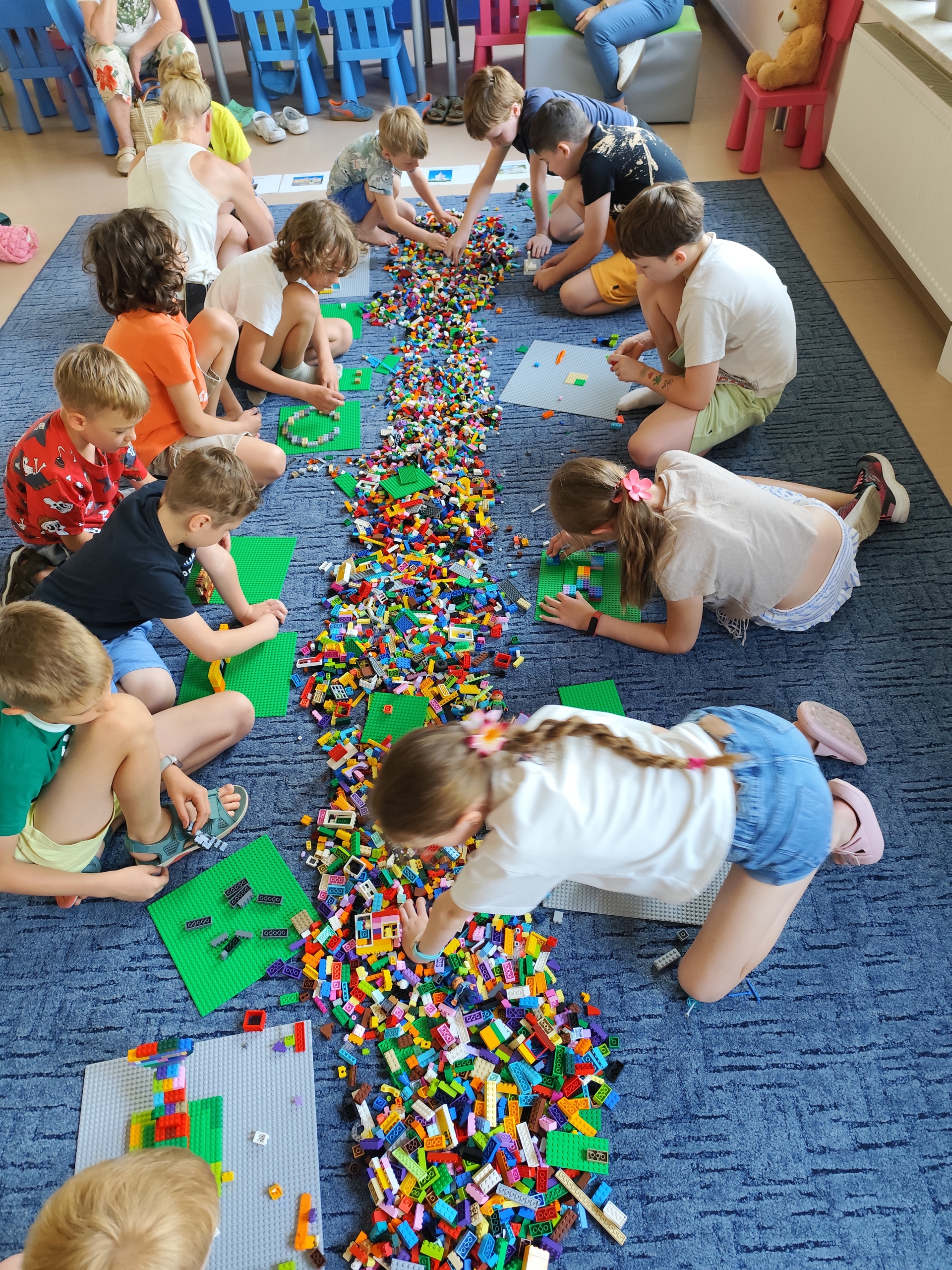 2 (15.07) Dzieci zgromadzone na dywanie, obok wysypanych elementów klocków LEGO.