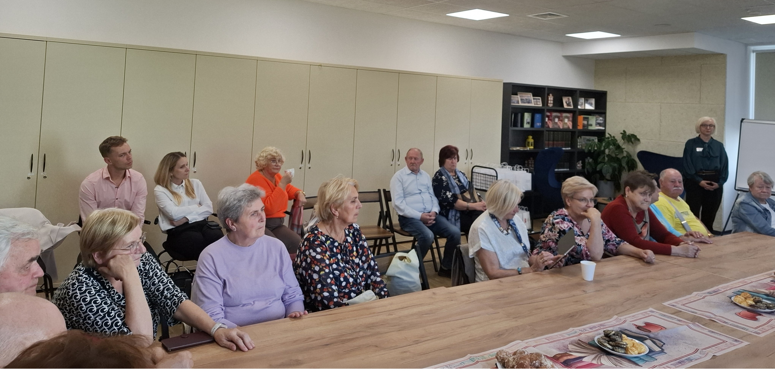 20260928_140213 Grupa ludzi siedzących przy stole w pomieszczeniu, prowadzących dyskusję.